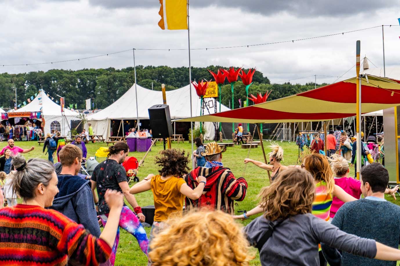 Emma Smallman hosting a Drum n Bounce class in a festival environment with a diverse crowd enjoying the routine. 